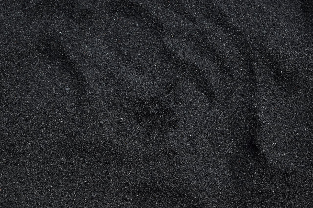 Home Close-up of black sand texture from Waimea Beach in Hawaii. Ideal for backgrounds.